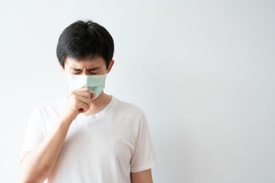 Portrait of young man standing against white background