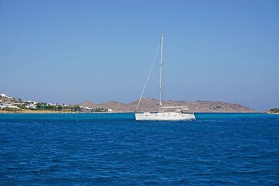 Sailboat in sea against clear blue sky