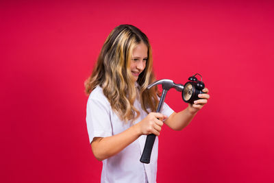 Portrait of young woman holding camera against yellow background