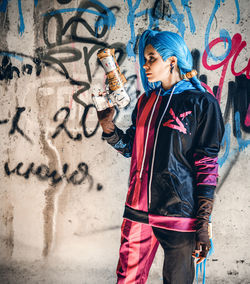 Rear view of woman standing against graffiti wall