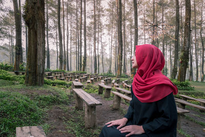 Rear view of woman with arms raised in forest