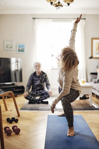 Senior woman stretching while doing yoga on exercise mat at home