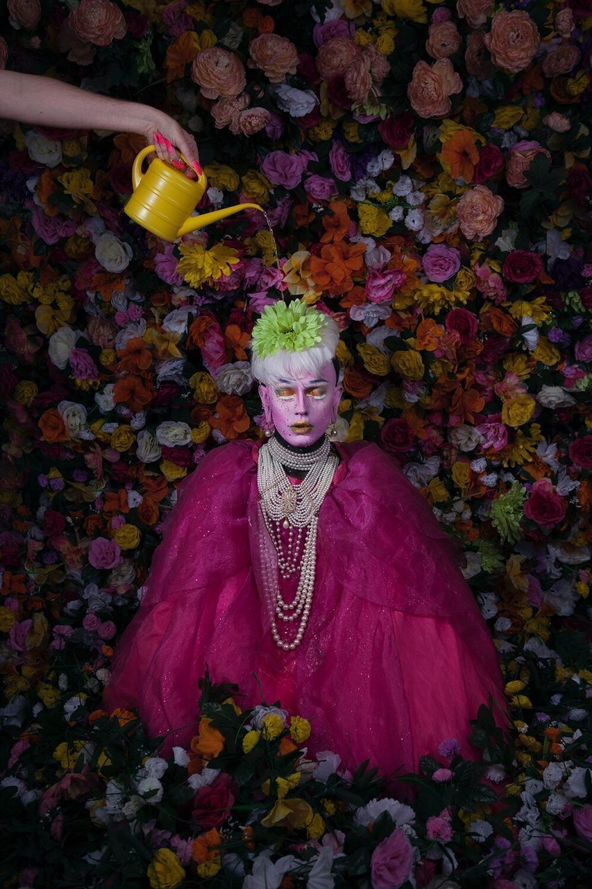 PORTRAIT OF YOUNG WOMAN WITH FLOWERS IN BACKGROUND