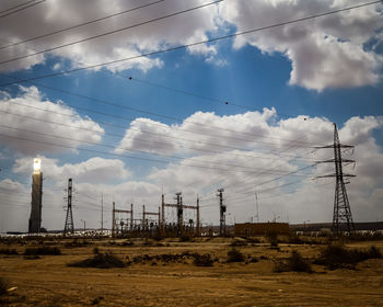 Low angle view of electricity pylon on field against sky