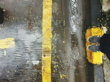 Low section of man standing on wet road