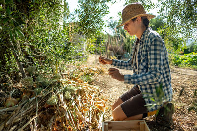 Young woman holding umbrella while relaxing on farm