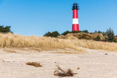 Lighthouse on field against clear blue sky