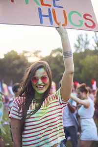 Portrait of happy woman holding free hugs sign at carnival