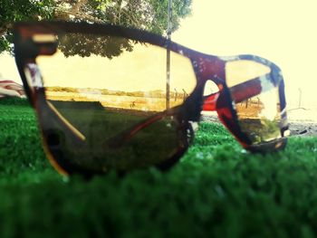 Close-up of sunglasses on grass against sky