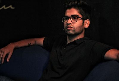 Man looking away while sitting in darkroom