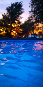 Surface level of swimming pool against lake at sunset