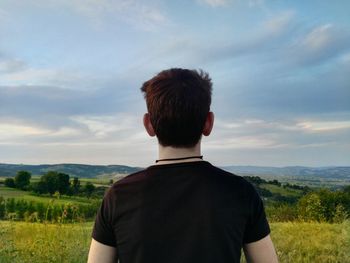 Rear view of man on field against sky