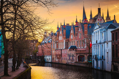 Canal amidst buildings against sky during sunset in city
