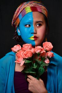 Close-up portrait of beautiful young woman against black background