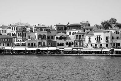 Buildings by sea against clear sky