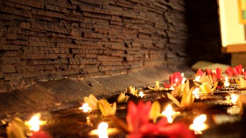 Close-up of illuminated candles on wall at night