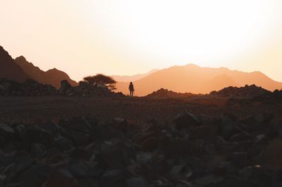 Silhouette people standing on land against sky during sunset