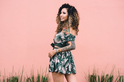 Rear view of woman looking away against wall outdoors