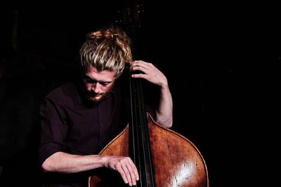 Mid adult man playing against black background