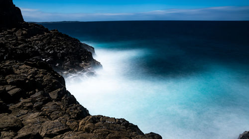 Rock formation by sea against sky