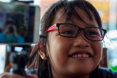 Portrait of an adorable asian little girl wearing glasses smiling.