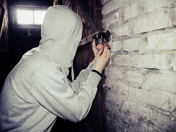 Hooded burglar opening padlock in basement