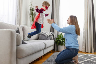 Side view of mother and daughter sitting on sofa at home