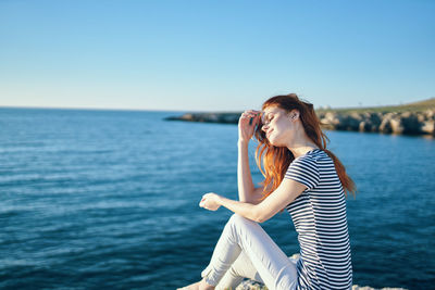 Woman sitting in sea against sky