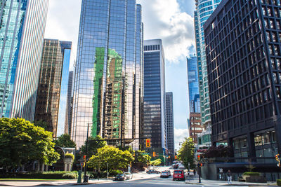 City street by modern buildings against sky