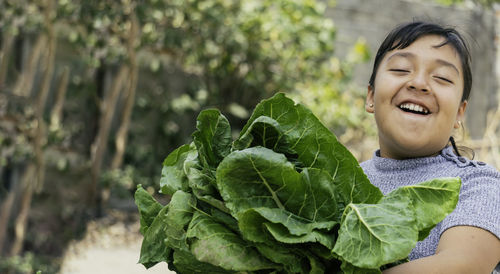 Portrait of smiling young woman holding leaf