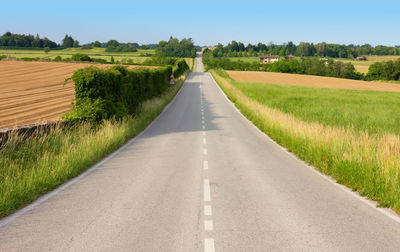 Road amidst field against sky