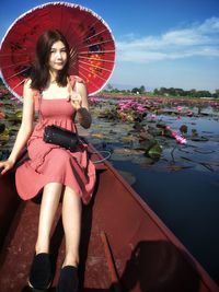 Portrait of beautiful woman with umbrella while sitting in boat on lake