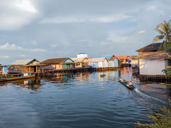 Stilt houses over lake against sky