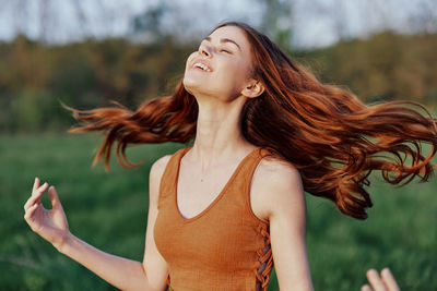 Young woman with eyes closed standing on field