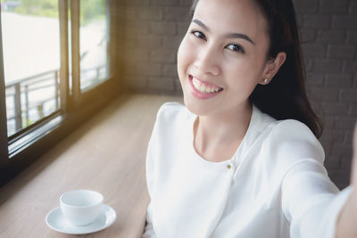 Portrait of smiling woman with coffee cup on table