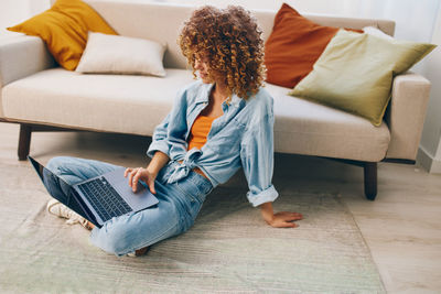 Rear view of woman sitting on bed at home