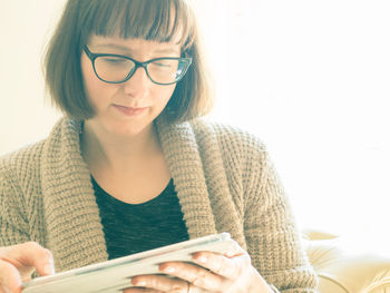 Close-up of mid adult woman using digital tablet against window at home