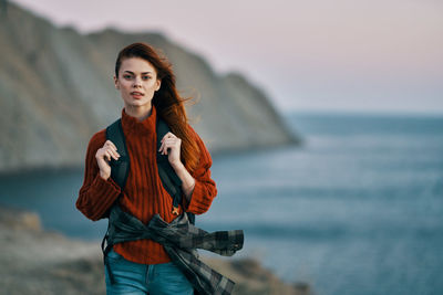 Portrait of young woman standing against sea