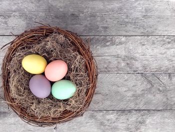 High angle view of colorful easter eggs in nest on wooden table