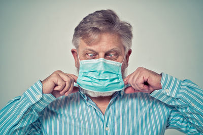 Portrait of man covering face against blue background