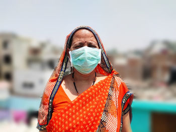 Portrait of mature woman wearing mask standing standing outdoors