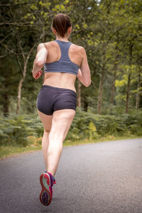 Rear view of woman with umbrella walking on road