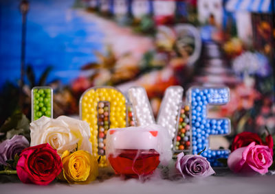 Close-up of multi colored roses with text decorations on table