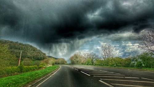 Country road against cloudy sky