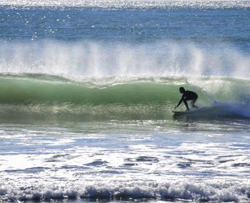 Man surfing in sea against sky during winter