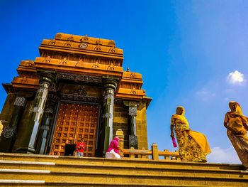 Low angle view of people woman on temple steps against blue sky