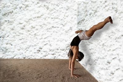 Mid adult woman with handstand against wall