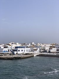 Sea by buildings against clear sky