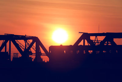 Silhouette of factory against sky during sunset