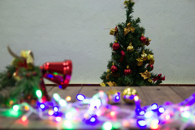 Illuminated christmas tree by wall